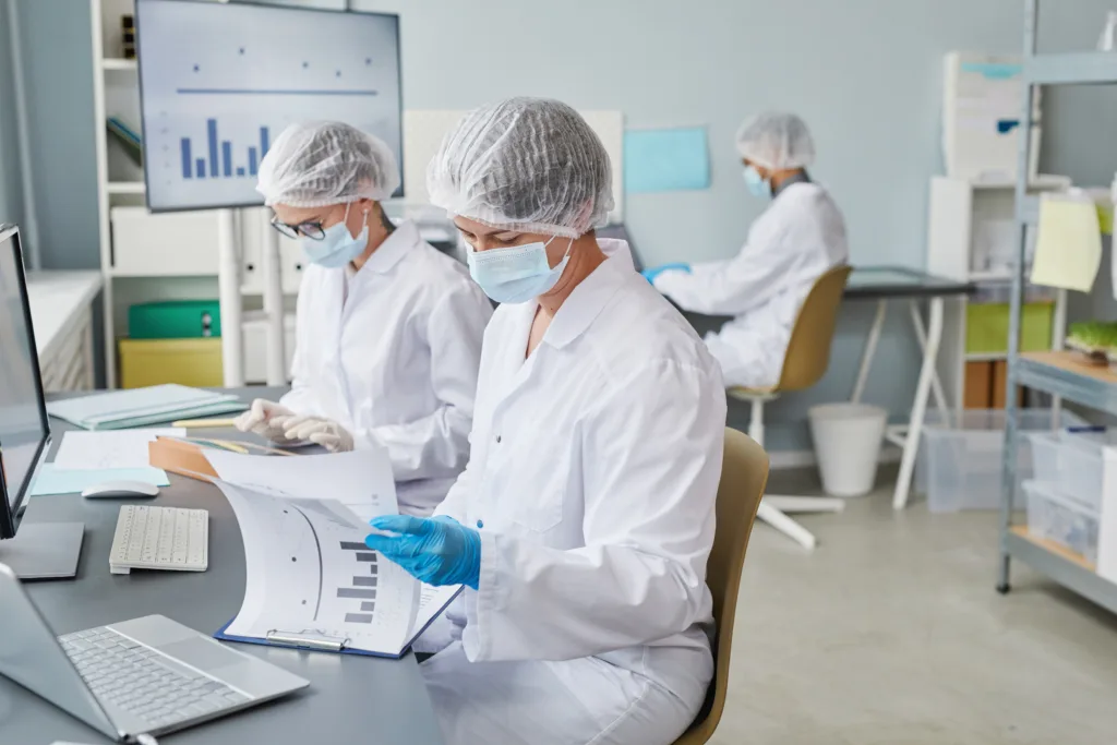 Group of scientists sitting at the table and working with statistics during pandemic in the laboratory